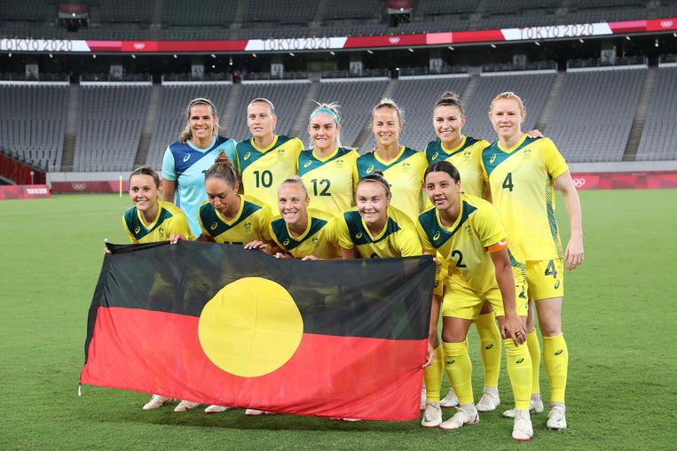 Australische voetbalelftal poseert met de Aboriginalvlag voor de wedstrijd tegen Nieuw-Zeeland op de Olympische Zomerspelen in Tokio in 2021. Australië zou met 2-1 winnen. Beeld AFP