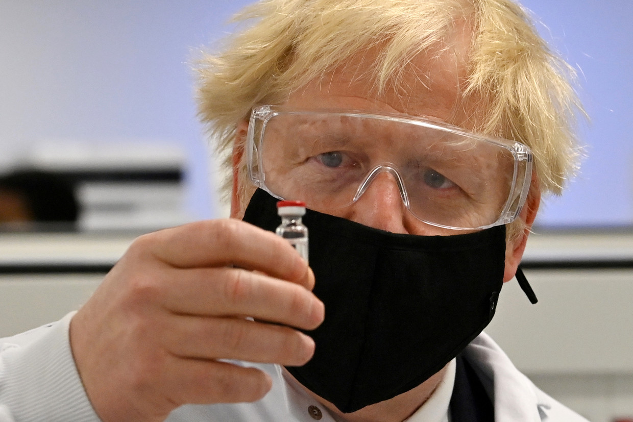De Britse premier houdt een flesje met het AstraZeneca/Oxford-vaccin vast. De Britten zouden het vaccin al voor Nieuwjaar goedkeuren. Beeld REUTERS