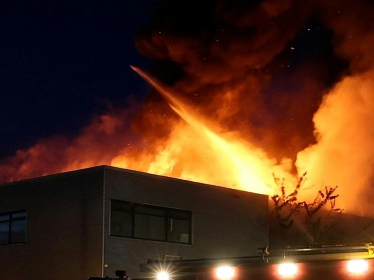 Grote vlammen stijgen op uit Amsterdams autobedrijf