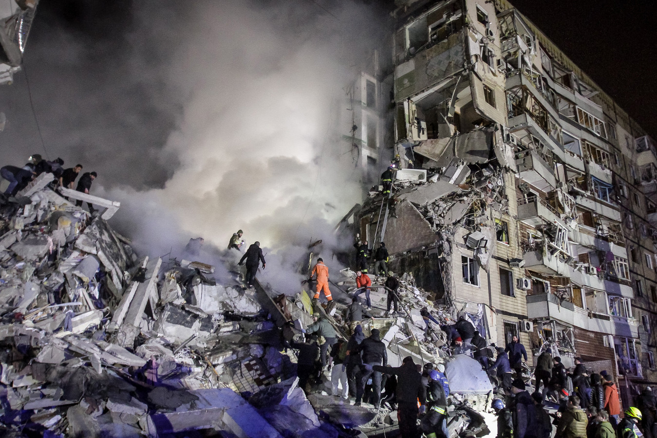 Inwoners helpen reddingswerkers bij het zoeken naar overlevenden van de raketaanval op het flatgebouw in Dnipro. (14/1/23)