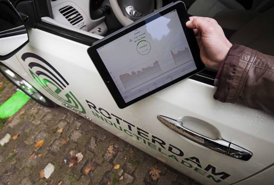 Een elektrische auto wordt opgeladen boven een laadplaat met behulp van een app.
