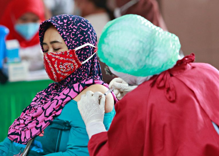 Een vrouw in Jakarta, Indonesië wordt ingeënt. Vaccinweigeraars in deze miljoenenstad riskeren een boete van omgerekend 300 euro. 
 Beeld Reuters