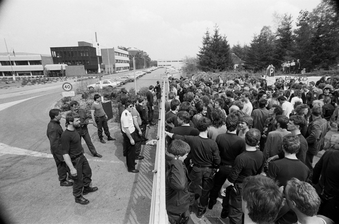 Tijdens een protest tegen kernwapens en kernenergie bij Vliegbasis Woensdrecht stellen bewaking en demonstranten zich op aan weerszijden van de poort.