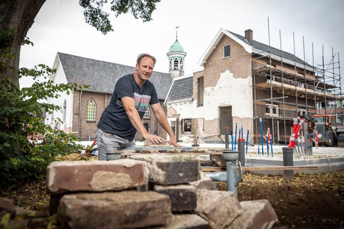 Marco Bergsma voor het parochiehuis en de hervormde kerk in Overdinkel. De aannemer geniet ervan om van een bijzonder pand weer iets moois te maken.