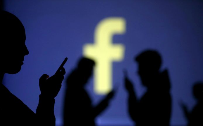 FILE PHOTO: Silhouettes of mobile users are seen next to a screen projection of Facebook logo in this picture illustration taken March 28, 2018.  REUTERS/Dado Ruvic/Illustration/File Photo