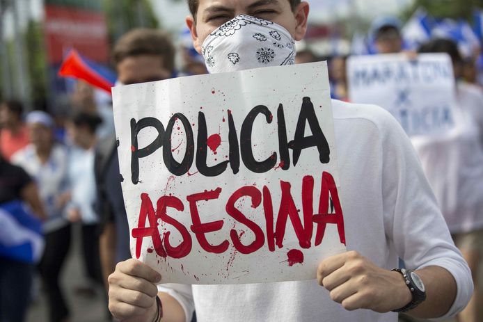 Demonstranten protesteren tegen de regering van Daniel Ortega in hoofdstad Managua.  Op het bordje staat 'politie moordenaar' ofwel 'de politie moordt'.