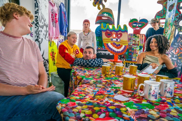 Deelnemers van Outsiderland en oprichter Jan Hoek (met ruitjesshirt en korte haren) in het nieuwe Sexyland World tegenover Amsterdam CS. Bruin Parry, met de geel en rode sweater, staat direct achter Hoek. Beeld Joris van Gennip