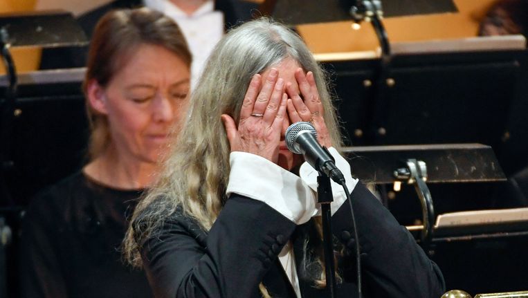 Patti Smith verbergt haar gezicht tijdens de uitreiking van de Nobelprijs voor de literatuur aan Bob Dylan. Beeld ap