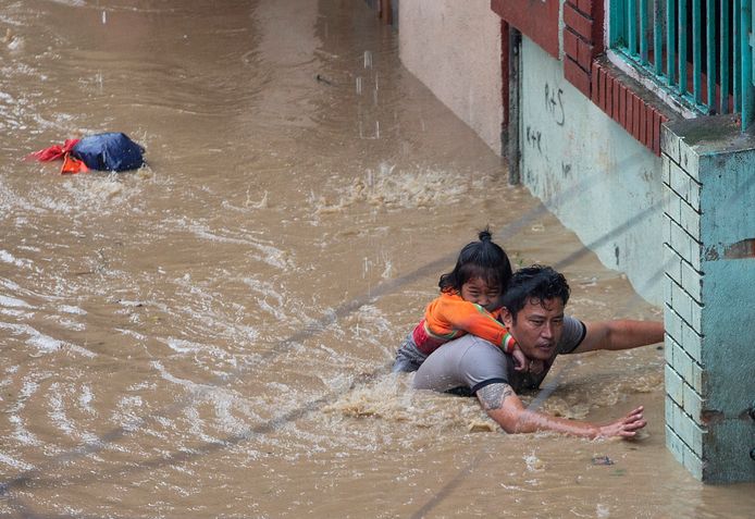 Een meisje klampt zich aan haar vader vast in een overstroomde regio in Kathmandu.