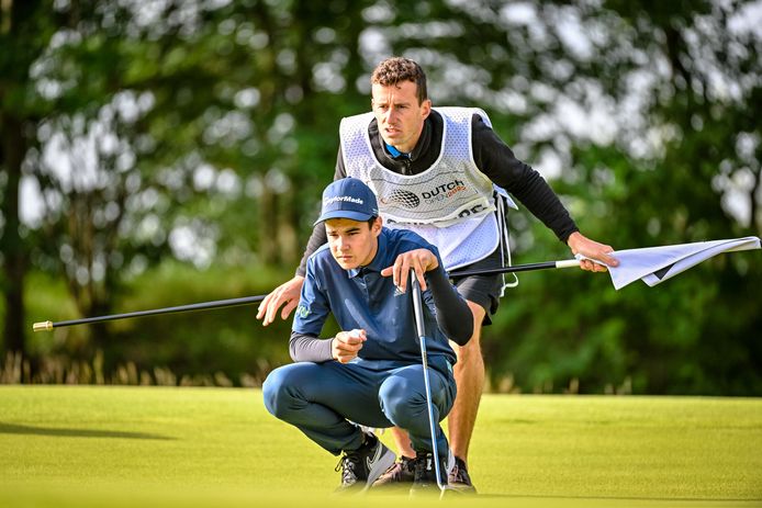 De 14-jarige Lev Grinberg bekijkt samen met zijn caddy de lijn van zijn bal bij het putten.