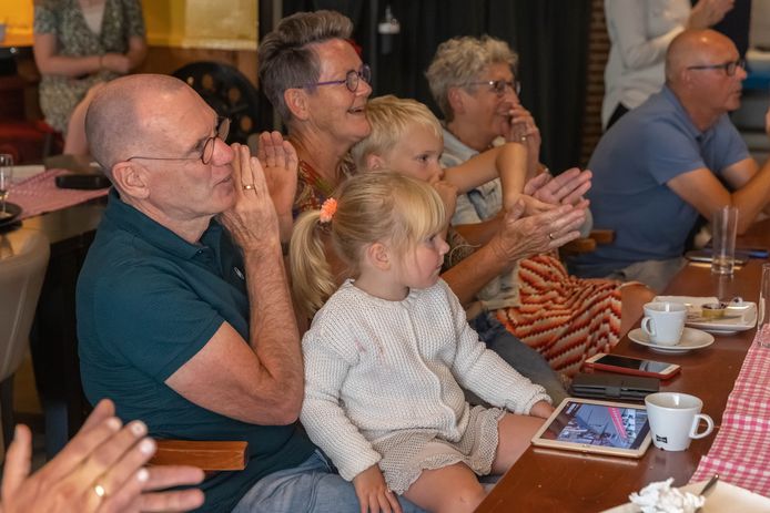 Herman van der Breggen (links) en zijn vrouw Marga kijken naar de koers in Tokio, kleinkinderen op schoot.