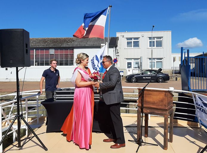Voorzitter Cees Otte van de visserijvereniging overhandigt een bloemetje aan Miss Visserij Dorien Padmos. Op de achtergrond hangt de Nederlandse vlag op z'n kop als teken van steun aan de boeren.