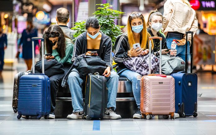 Drukte in de vertrekhallen van Schiphol met mensen die deze zomervakantie op reis gaan naar het buitenland.