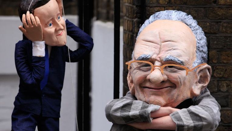 Protest met karikaturale poppen van de Britse premier Cameron (links) en Rupert Murdoch voor het appartement van Cameron, vandaag. Beeld reuters