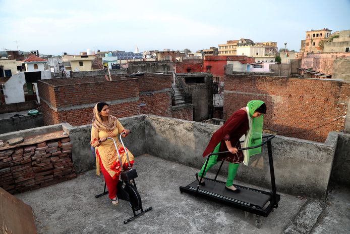 Twee Indische vrouwen sporten thuis op het dak van hun woning in Jammu.