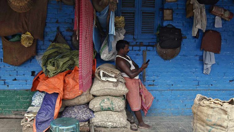 Marktkoopman met mobiele telefoon in Kolkata, India. Beeld Rupak De Chowdhuri / Reuters