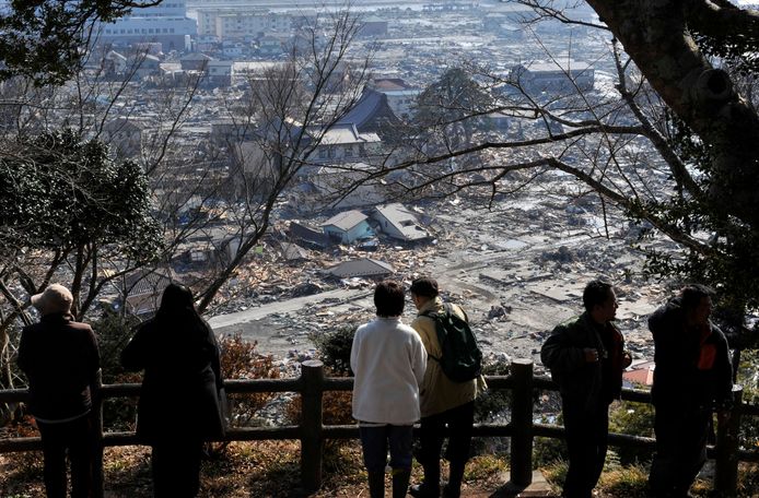 Overlevers van de tsunami zien de resten van hun stad in 2011.