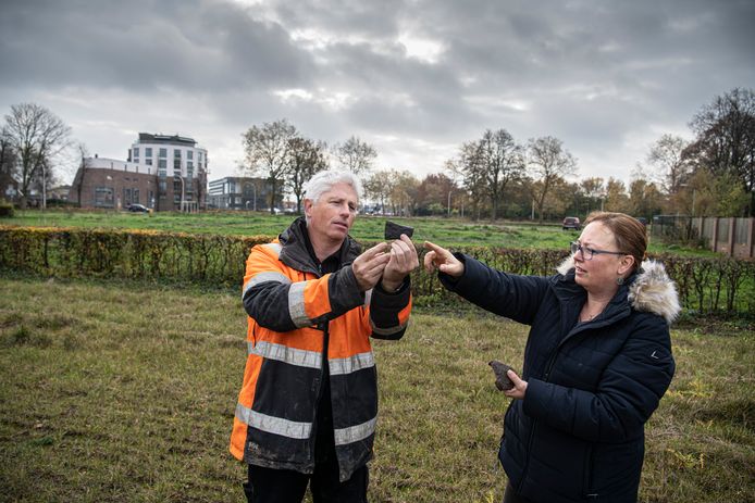 Archeoloog Roy van Mousch van archeologisch onderzoeksbureau BAAC toont de kokerbijl aan Ester van der Linden, archeoloog van de gemeente Druten. De twee staan op de plek waar de bijl werd gevonden, waar vroeger basisschool De Dijk zat.