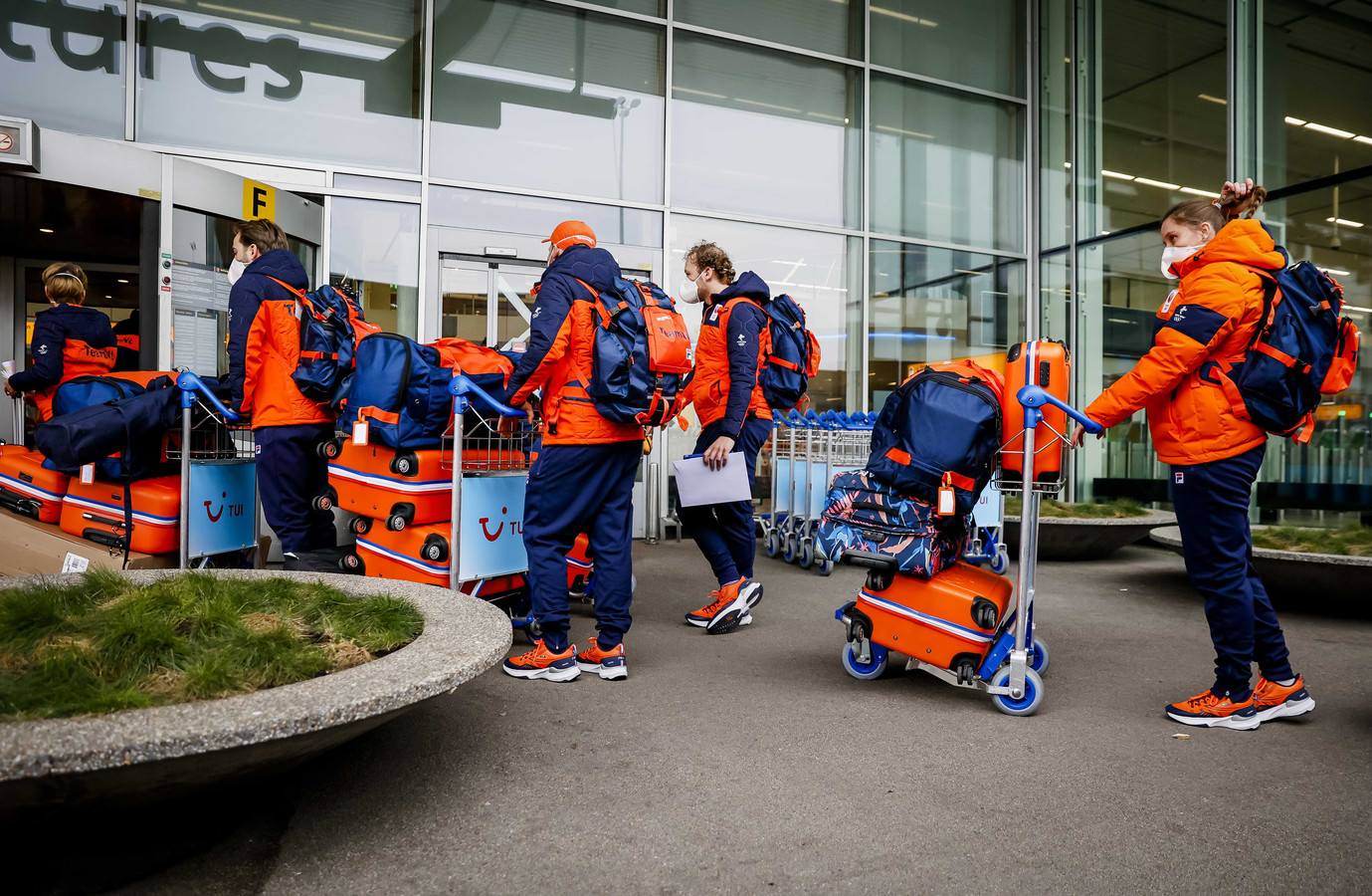 Olympiers met hun koffers bij de vertrekhal voorafgaand aan de vlucht naar de Chinese hoofdstad Peking.