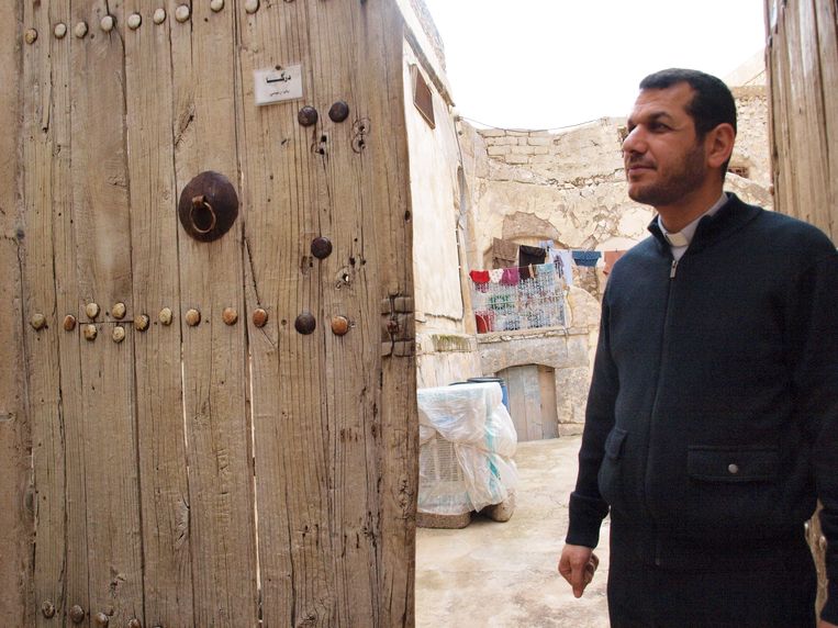 Vader Araam bij een oude deur die hij gered heeft en die nu toegang geeft tot een museumpje over het recente verleden van Al Qosh. Beeld Judit Neurink