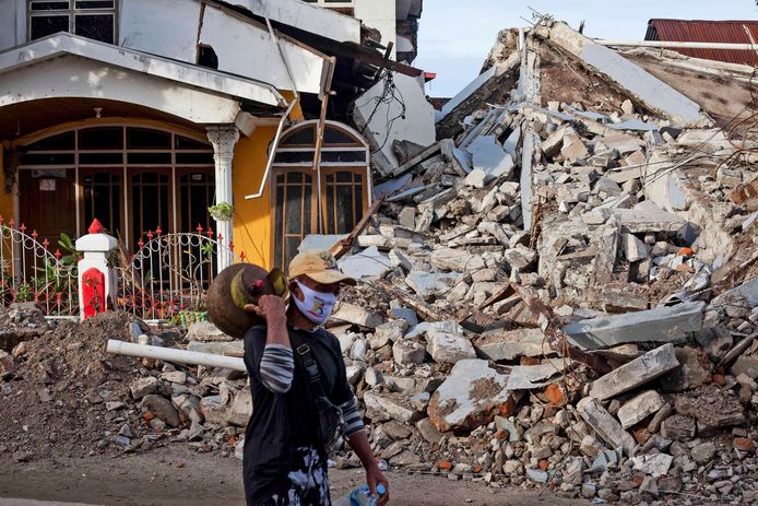 Een man loopt langs een ingestort huis in Sulawesi, Indonesië.