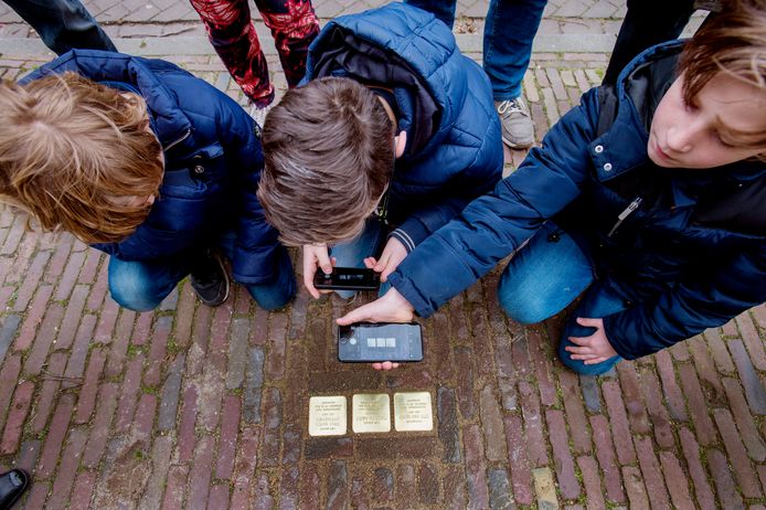 Scholieren maken in Oisterwijk met hun mobieltjes een foto van struikelstenen, die herinneren aan Joodse slachtoffers van de Holocaust.