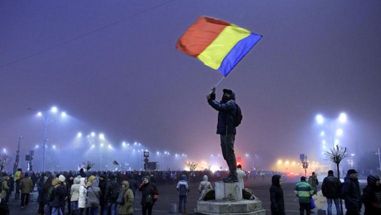 Roemeense jongeman zwaait met de nationale vlag in een demonstratie voor de regeringsgebouwen, 6 februari. Beeld epa