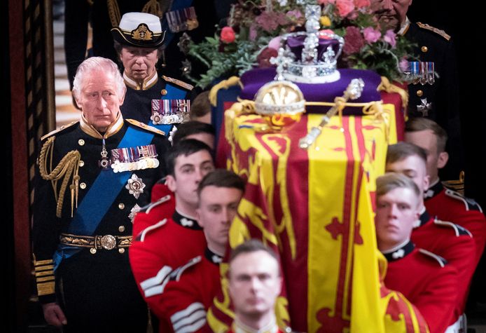 Koning Charles loopt naast de kist terwijl deze uit Westminster Abbey wordt gedragen.