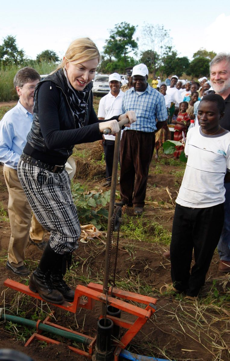 Madonna pompt water omhoog bij een project van haar stichting Raising Malawi. Ze ligt inmiddels overhoop met de medewerkers. Beeld REUTERS