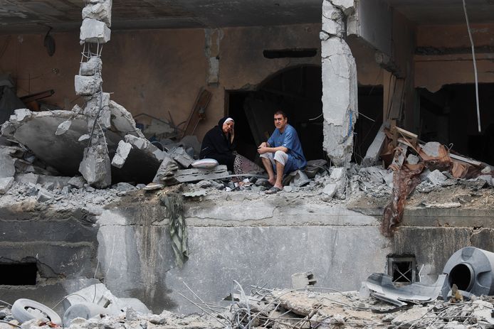 Palestijnen zitten tussen het puin van een vernield gebouw na de Israëlische aanvallen in Gaza.