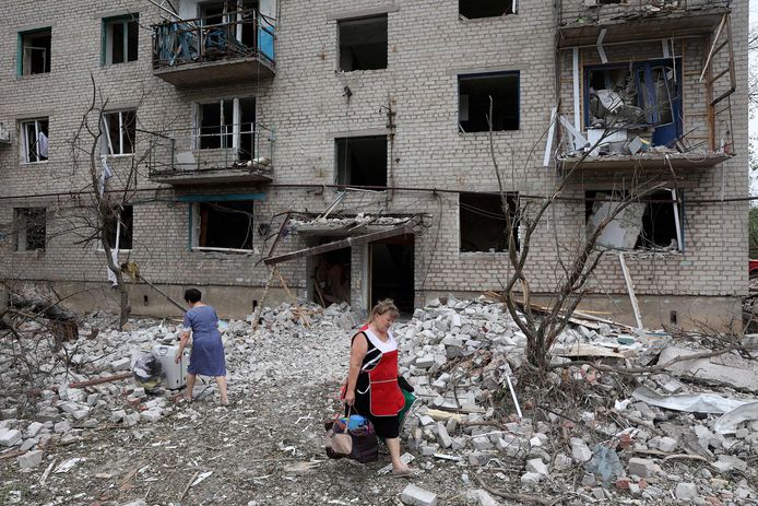 Een vrouw draagt haar bezittingen weg na de Russische raketaanval op een flatgebouw in Chasiv Yar.