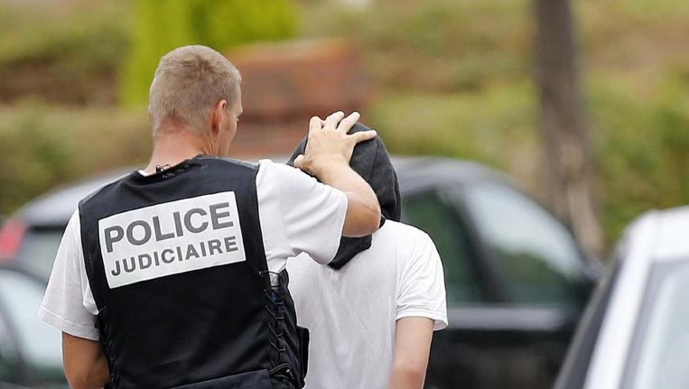 Agenten arresteren een verdachte na de moord op priester Hamel in Saint-Etienne-du-Rouvray. Een van de daders droeg een enkelband. Beeld afp