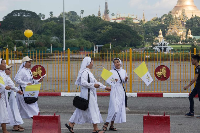Burmese nonnen houden Vaticaan-vlaggen vast. Ze wachten tot Paus Franciscus langs zal rijden.   Beeld AFP