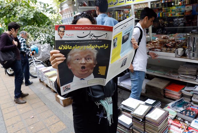 Een Iraanse vrouw  leest een krant met Trump op de voorpagina. De Amerikaanse president is groot tegenstander van de kerndeal  het land.