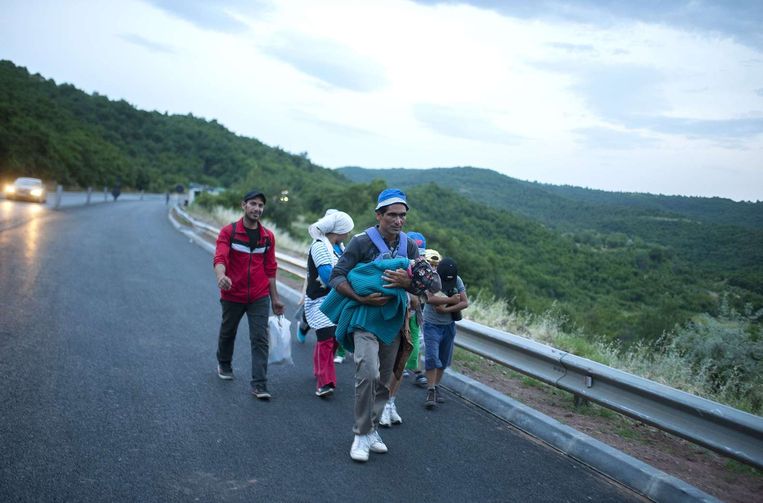 Vluchtelingen lopen over de weg bij Veles in Macedonië, de 'Balkanroute' om in de EU te komen. Beeld AFP