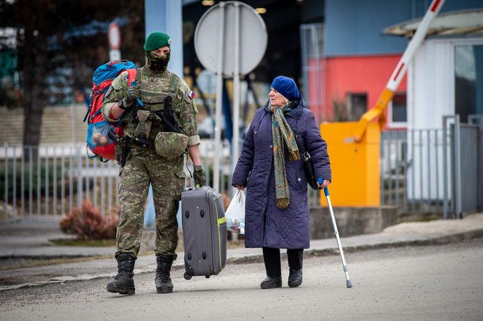 Een Slovaakse soldaat helpt een Oekraïense vrouw met haar bagage aan een grenspunt in Vysne Nemecke, Slovakije.