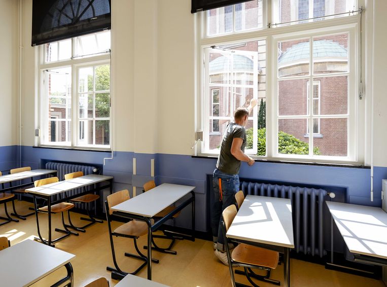 Een leraar zet de ramen open tijdens de voorbereidingen voor het begin van het nieuwe schooljaar.  Beeld ANP