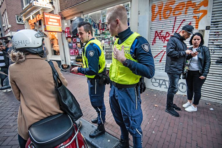Boa's waarschuwen in het centrum van Amsterdam een vrouw op de scooter die op deze plek niet mag rijden. Beeld Guus Dubbelman / de Volkskrant
