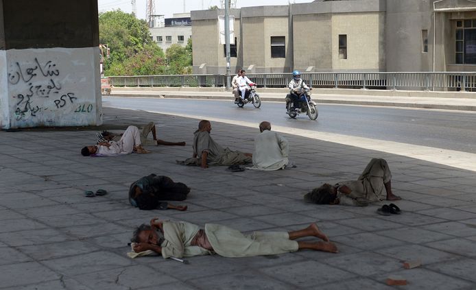 Mannen in het Pakistaanse Karachi zoeken beschutting onder een brug tijdens de hittegolf van 2015. Duizenden mensen, onder wie veel daklozen, kwamen destijds om het leven.