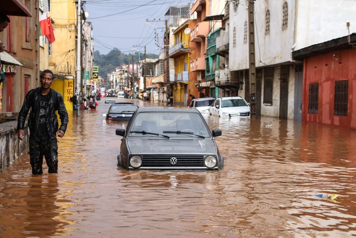 A resident walks through floodwaters past submerged vehicles on a road in Antananarivo on January 8, 2020, after heavy rainfall. (Photo by MAMYRAEL / AFP)