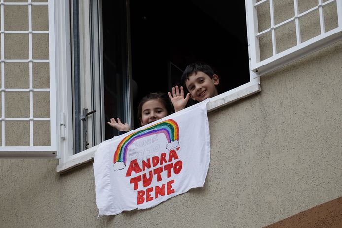 De kleine Francesco and Greta Innominati zwaaien vanuit hun flat in Rome bij hun zelfgemaakte banner met de tekst "Alles komt goed'.