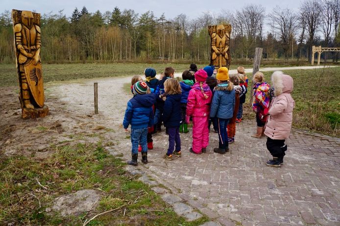 Kinderen staan voor de houten ridders die bij de ingang van het speelbos in het Mastbos bij Breda zijn geplaatst.