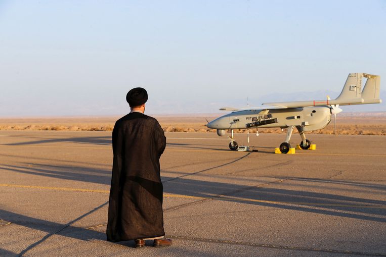 Een Iraanse geestelijke staat naast een drone tijdens een militaire oefening.  Beeld via REUTERS