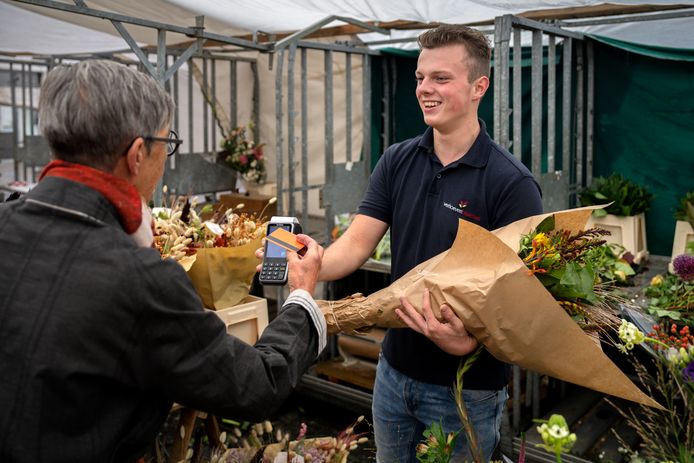 Frank Verhoeven (16) staat met bloemen op de markt van Zaltbommel.