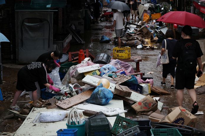Mensen ruimen een overstroomde markt op in Seoul.