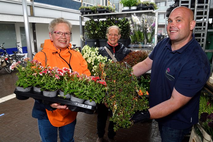 Bloemist Cees van der Plas geeft Rita Cazemier gratis plantjes, op de achtergrond staat dochter Saskia.