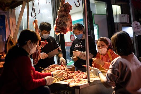 Verkopers met mondkapjes prepareren een barbecue op een markt in Wuhan in de provincie Hubei.