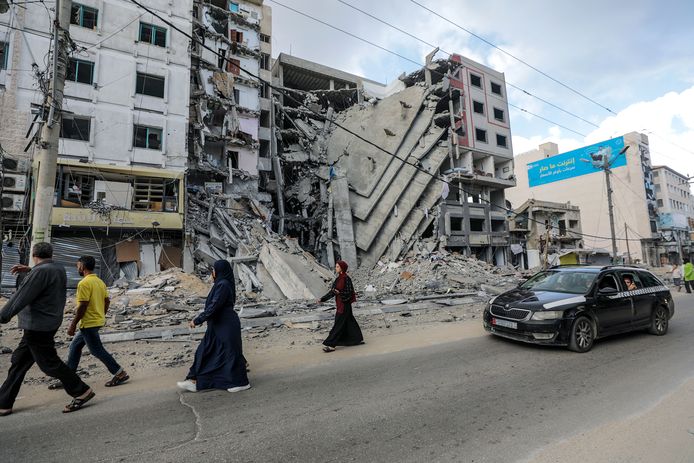 Palestijnen wandelen langs verwoeste gebouwen in Al Remal, Gaza.