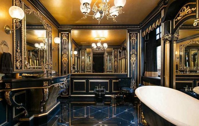 Een van de badkamers met zwarte tegels en heel veel goud.