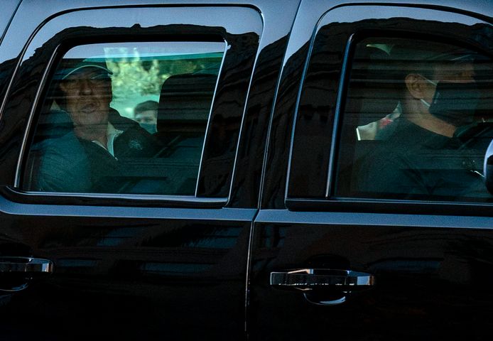 Donald Trump kijkt vanuit de wagen op weg naar het Witte Huis.